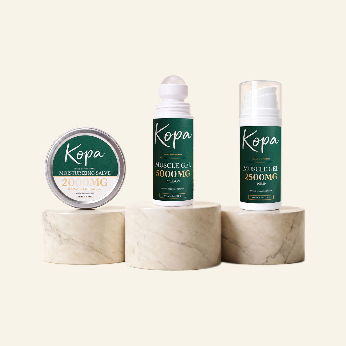 The Kopa Complete Set on marble pedestals: Moisturizing Salve 2000mg tin, Muscle Gel Roll-On 5000mg, and Muscle Gel 2500mg pump