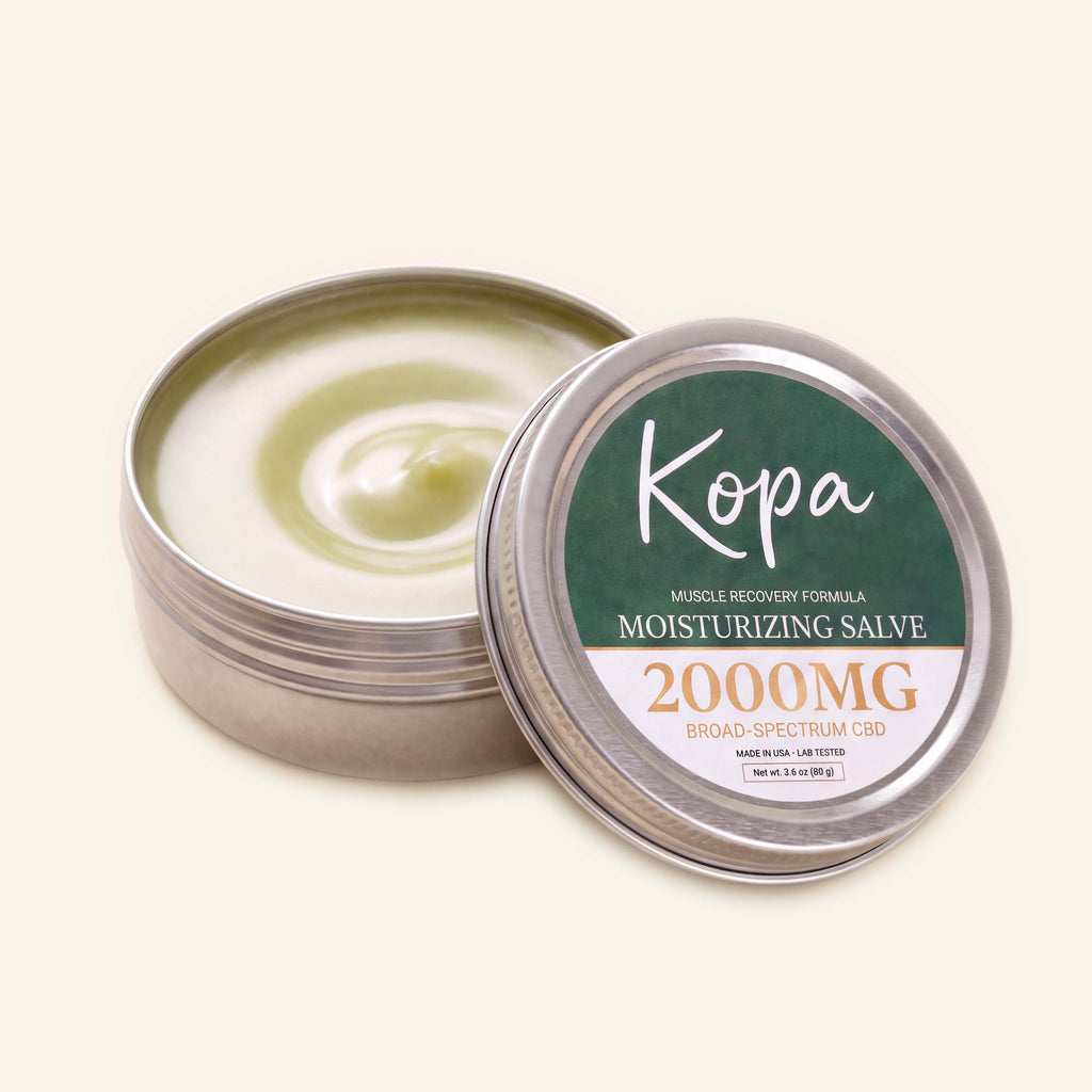 Kopa Moisturizing Salve tin open, showing the pale green balm inside with the lid resting against it